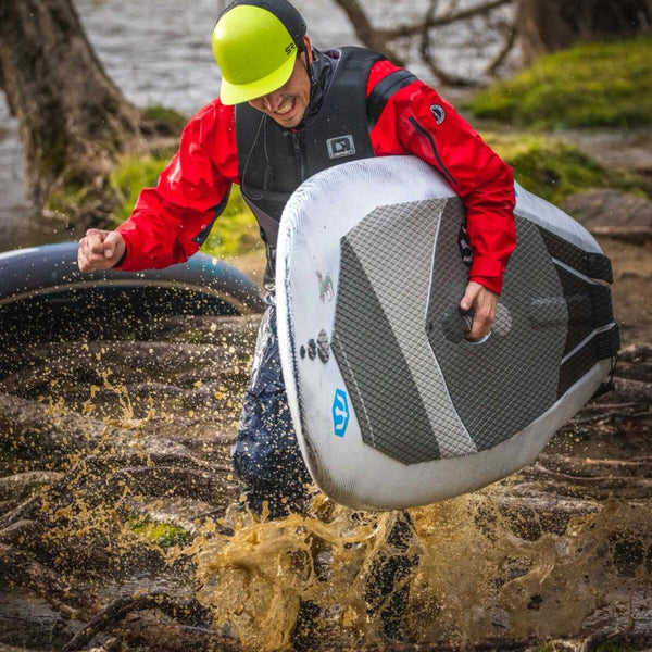 A paddler in a helmet flipping a Hydrus board out of a river with water spray
