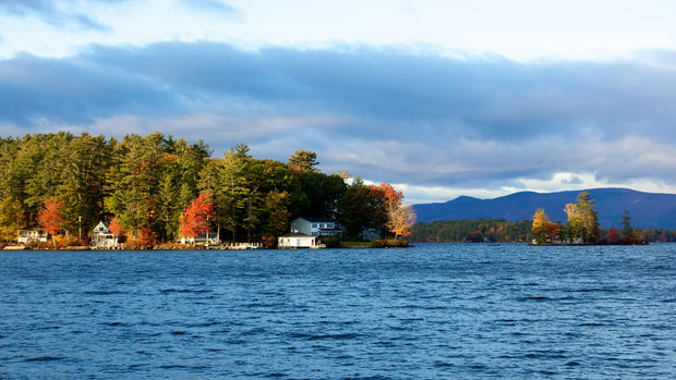 Paddleboarding on Lake Winnipesaukee, New Hampshire, with forested shoreline and White Mountains