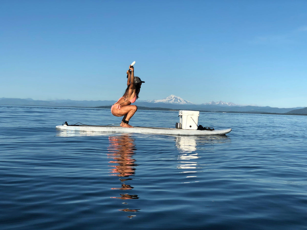 Paddler at sentence-pace effort on an inflatable Hydrus paddleboard, blade planted, torso rotated. Programmed paddling as full-body cardio training.