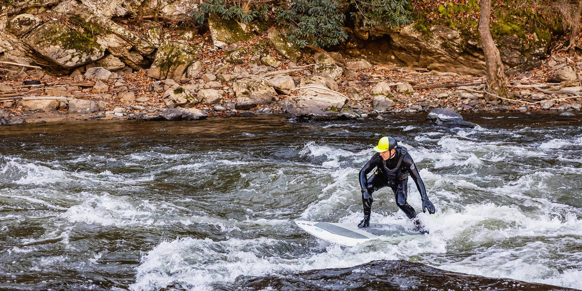 River surfer riding a hard paddle board on a whitewater wave